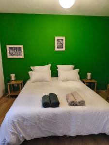 a green bedroom with a large bed with two pairs of slippers at Ostal del Koï in Rabastens