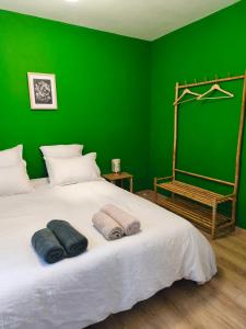 a green bedroom with a bed with two towels on it at Ostal del Koï in Rabastens