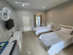 a room with two beds and a fan and a tv at Vanilla Ville Resort in Khlong Thom