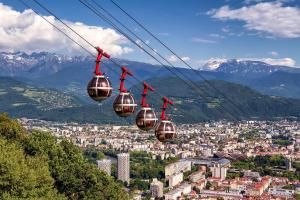 a gondola ride over a city in the mountains at La forêt, T3 Design, Parking, Face à la Gare in Grenoble