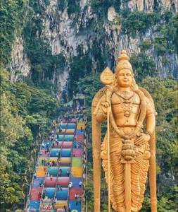 a statue in front of a mountain with a line of colored cars at STAR Hotel Apartment in Kuala Lumpur