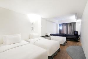 a hotel room with two beds and a couch at Hotel 498 in Incheon