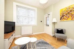 a living room with a tv and a table at Cosy town centre cottage in Peebles