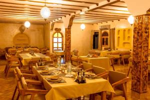 a restaurant with tables and chairs with yellow table cloth at Hotel Sunset Palace Merzouga in Merzouga +59 photos
