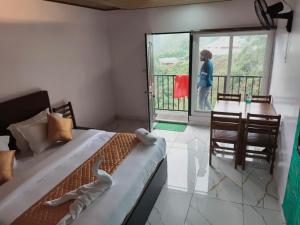 a bedroom with a bed and a desk and a woman standing on a balcony at Hill view cottage cj in Devikolam