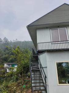 a house with a staircase leading up to a window at Hill view cottage cj in Devikolam