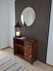 a bathroom with a mirror and a table with a lamp at Lägenhet nära naturen Pralinette BB in Nykroppa