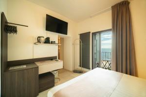 a bedroom with a bed and a television and a balcony at Le Contrade Di San Salvatore in Monopoli
