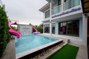 a swimming pool with a slide in front of a house at BanIngKhao Pool Villa Sriracha in Ban Hup Bon