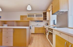 a kitchen with wooden cabinets and white counter tops at Chalupa u golfu Kořenec in Kořenec