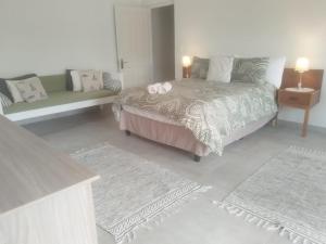 a bedroom with a bed and a couch and rugs at Lavender Suite in Gansbaai
