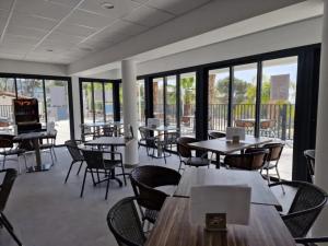 a dining room with tables and chairs and windows at Camping de Ceyreste - Maeva in La Ciotat
