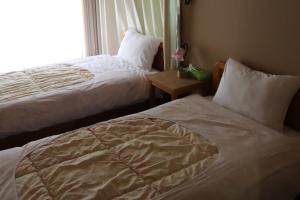 a hotel room with two beds and a window at ペンション愛宕道 in Kyoto