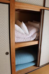 a small wooden shelf with pillows and towels on it at ペンション愛宕道 in Kyoto +4 photos