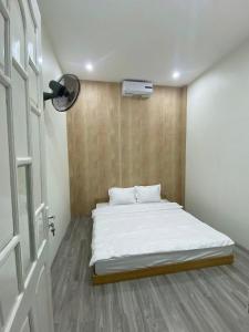 a small bedroom with a white bed and a door at Homestay Lumina in Dong Hoi