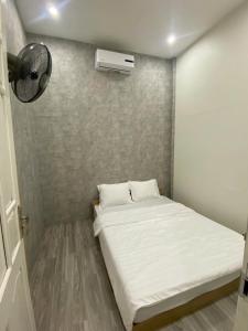 a small room with a bed and a fan at Homestay Lumina in Dong Hoi