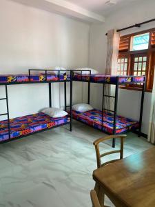 a room with three bunk beds and a table at Chandani Hostel in Galle