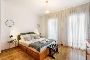 a bedroom with a bed with white walls and wooden floors at Sunny Beachside Escape by Minho's Guest in Póvoa de Varzim