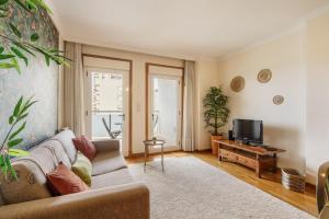 a living room with a couch and a tv at Sunny Beachside Escape by Minho's Guest in Póvoa de Varzim