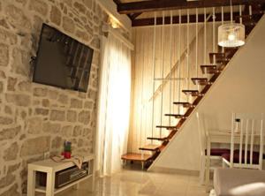 a living room with a staircase with a tv on a stone wall at Menego Lodge Bol in Bol