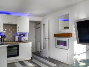 a kitchen with white cabinets and a tv on a wall at Holly's Apartment in Beverley