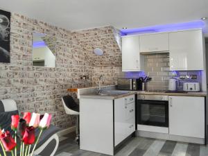 a kitchen with white cabinets and a brick wall at Holly's Apartment in Beverley