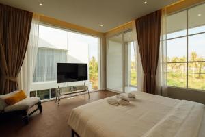a bedroom with a bed and a tv and large windows at PRAN MARE Pranburi in Ban Nong Ban Kao +28 photos