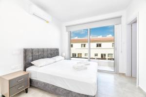 a bedroom with a white bed and a large window at Rons House in Paralimni