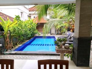 a swimming pool in the middle of a garden at Jepun Segara Guest House in Kuta
