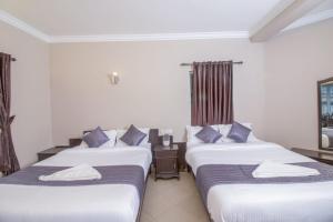 three beds in a hotel room with blue pillows at Mounts shelts in Munnar