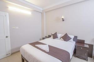 a bedroom with a large white bed with a night stand at Mounts shelts in Munnar