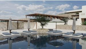 a swimming pool with lounge chairs and an umbrella at Agali Hotel Milos in Adamantas