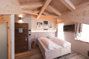 a bedroom with a white bed and a wooden ceiling at Chalet Vites Mountain Hotel in Canazei