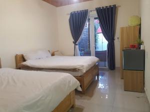 two beds in a room with a window and a television at Mây Villa Garden Đà Lạt in Xuan An