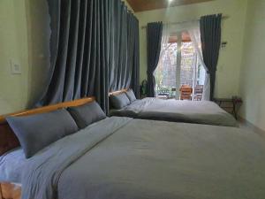 a bedroom with two beds and a window with curtains at Mây Villa Garden Đà Lạt in Xuan An