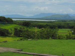 a green field with a lake and mountains in the background at The Golfing Shepherd in Mba