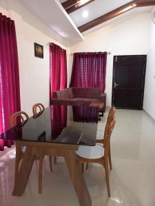a dining room with a table and chairs and red curtains at WHITE FLOWER mountain resort in Perintalmanna