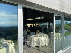 a restaurant with white tables and chairs and windows at Cantina dei 5 Sogni in Monforte dʼAlba +22 photos