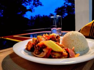 a plate of food with rice on a table at Rainforest River Bay in Deniyaya