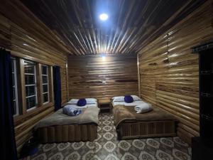 a room with two beds in a wooden cabin at Manjosila Homestay in Mirik