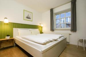 a large white bed in a room with a window at Captain Pahlen Ferienanlage in Zingst