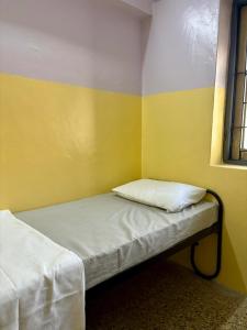 a small room with a bed with a pillow on it at Urban Mansion Triplicane in Chennai