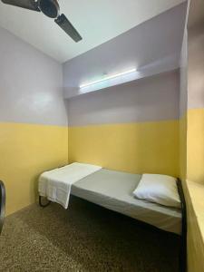 a small room with a bed with yellow and white walls at Urban Mansion Triplicane in Chennai