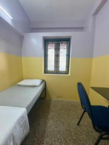 a room with two beds and a table and a window at Urban Mansion Triplicane in Chennai
