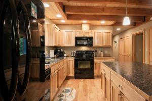 a large kitchen with wooden cabinets and black appliances at Paws in the Mountains by NW Comfy Cabins in Leavenworth +37 photos