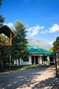 a white house with a green roof and a tree at LASplore munnar in Kallar Vattiyar