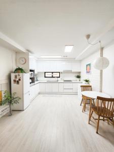 a kitchen with white cabinets and a table and chairs at Kintex Central Stay 3BR 2Bath Spacious Space in Ilsan-yŏk