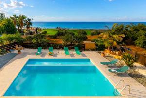 a swimming pool with chairs and the ocean in the background at Villa Adonis Large Private Pool Walk to Beach in Argaka