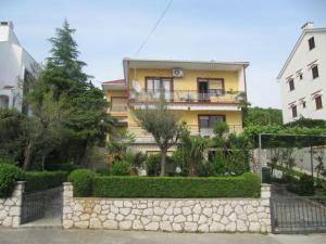 a yellow building with a stone fence in front of it at Fran in Crikvenica