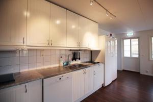 a kitchen with white cabinets and a sink and a refrigerator at GrebbestadFjorden vandrarhem in Grebbestad +14 photos